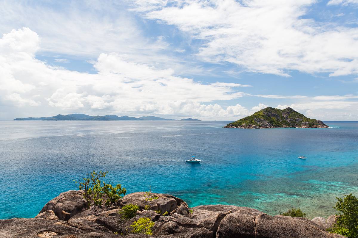 Leave the disasters behind Two boats are anchored in beautiful blue water among tropical islands